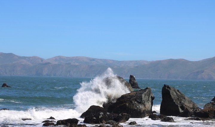 a wave in the Pacific Ocean at Lands End crashing into a rock at Mile Rock Beach in San Francisco, California