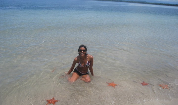 Girl in ocean surrounded by starfish