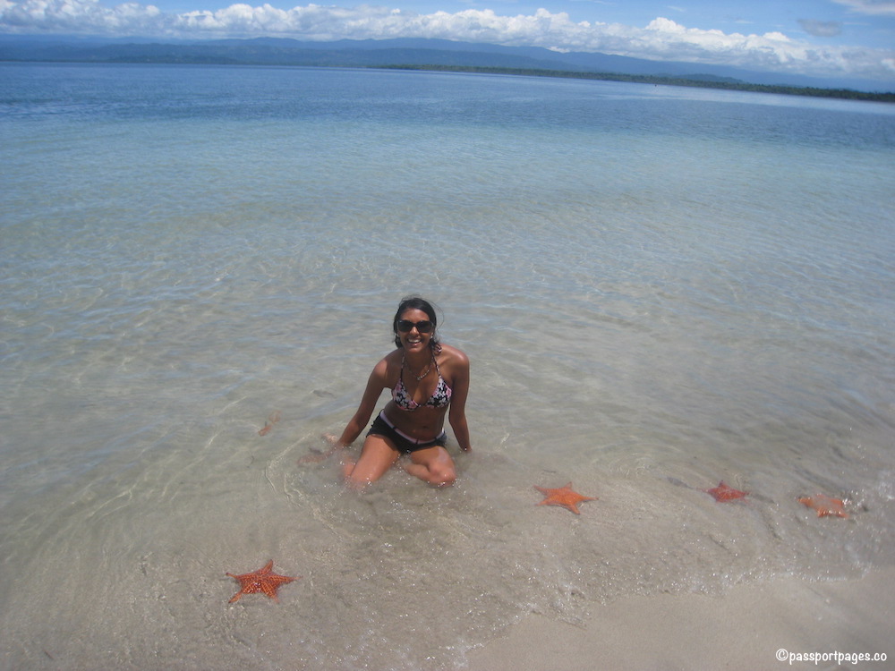Girl in ocean surrounded by starfish